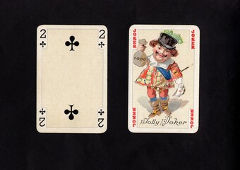 A pair of vintage playing cards featuring a joker isolated on a black background.