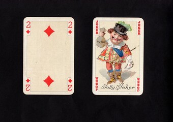 A pair of vintage playing cards featuring a joker isolated on a black background.