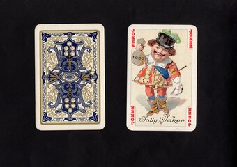 A pair of vintage playing cards featuring a joker isolated on a black background.