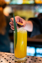 Bright yellow cocktail with crushed ice, half a passion fruit, and green leaf garnish in a tall...