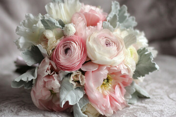 Obraz premium Beautiful bouquet featuring soft pink ranunculus and delicate white flowers on elegant fabric background