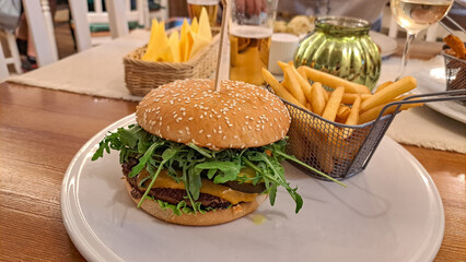 delicious burger with arugula, and next to it fries and beer