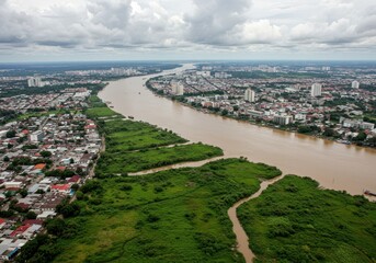 Fototapeta premium Aerial view of a city with a wide river flowing through it under a cloudy sky