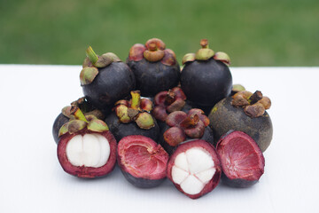 Fresh Thai mangosteens, some opened to reveal their juicy white flesh, are displayed on a clean surface. A seasonal tropical fruit known for its sweet taste, rich nutrients, and natural antioxidants.
