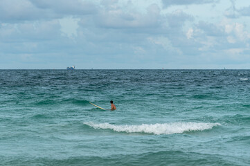 surfer waiting for a wave on a cloudy day beach