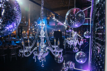 Crystal chandeliers paired with disco balls create a striking visual at a stylish event. The...