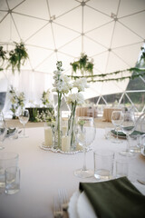 Wedding venue table elegantly set with white flower centerpiece in glass vases. Pearls and candles...