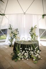 Wedding reception setup with a beautifully decorated table featuring lush green and white floral arrangements. A sophisticated atmosphere inside a stylish venue enhances the celebratory mood.