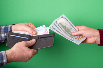 Man and woman exchanging cash currency: US dollars, Ukrainian hryvnias. A man takes out hryvnia...