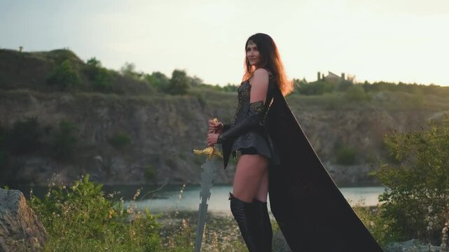 Fantasy woman viking princess warrior. Warlike girl Amazon. Lady nordic style sexy valkyrie goddess holding sword in hand. Leather costume armor cloak flies in wind. Mountains sunset sky nature summer