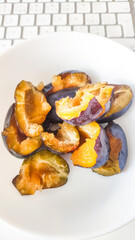 Stewed plums in a bowl next to a keyboard, healthy office snack