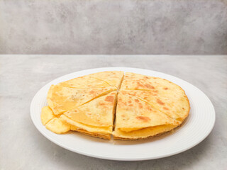 Quesadilla cut into slices, lying on a white plate and ready to be served, copy space