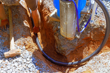 Workers are installing water laying pipe at construction site, digging in ground under works day