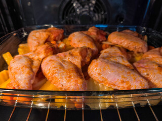 Fototapeta premium Delicious chicken wings baking with potatoes and carrots in oven