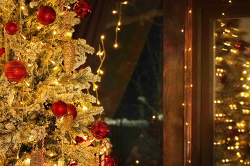 Decorated Christmas tree with red ornaments and warm lights in cozy room during winter season