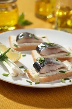 Herring pieces served on toast on yellow background