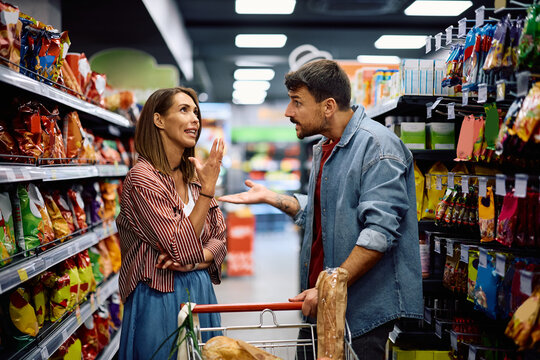 Displeased man having a conflict with his wife during a shopping in supermarket. - Powered by Adobe