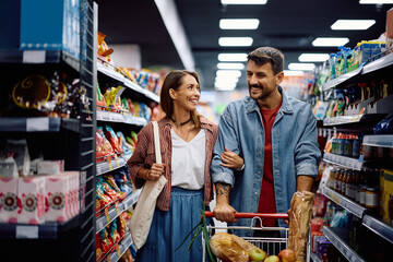 Happy couple talking while enjoying in shopping at supermarket.