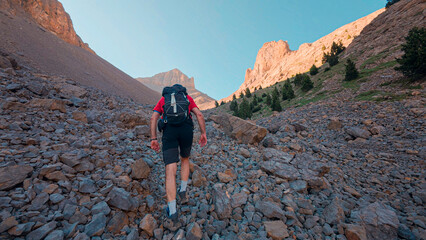 Challenging ascent of the Agujas de Lavasar in the Aragon Pyrenees, a mountaineer traverses rocks and towering mountains, enjoying views of the Ibon de Lavasar in the Chistau Valley.
