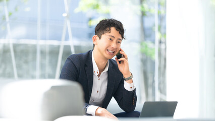 スマートフォンで通話をする笑顔の男性ビジネスマン