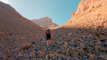 Mountaineer ascending the Agujas de Lavasar in Aragon, overcoming the rocky terrain with the impressive mountains and the Ibon de Lavasar in the background, creating a stunning natural landscape.
