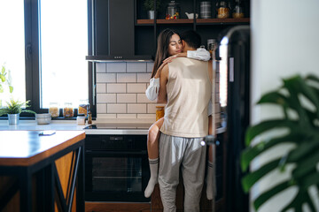 Romantic couple embracing in a modern kitchen, sharing tender moments and enjoying the warmth of their intimate connection together