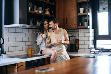 Romantic couple sharing a moment while drinking coffee in their contemporary kitchen, enjoying the start of the day together