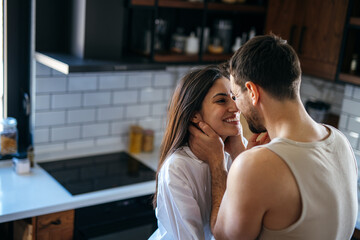 Romantic couple sharing a tender moment in their modern kitchen, enjoying each other's company and creating a warm, intimate atmosphere