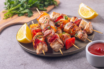 Delicious grilled chicken skewers with capsicum, lemon, salad and ketchup on a plate over the table. Chicken kebab. Healthy food concept.