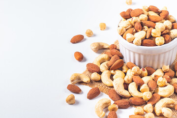 Large assortment of nuts in different bowls on stone table.