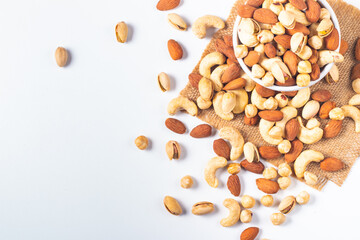 Large assortment of nuts in different bowls on stone table.