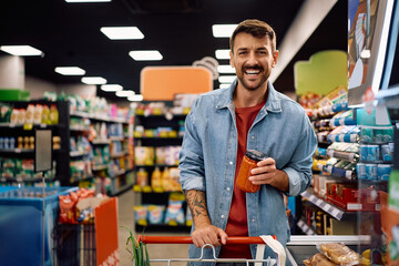 Satisfied supermarket customer at the checkout looking at camera.