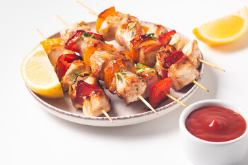 Delicious grilled chicken skewers with capsicum, lemon, salad and ketchup on a plate over the table. Chicken kebab. Healthy food concept.