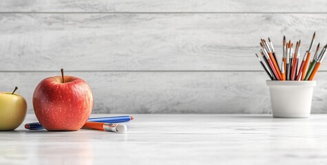 Photo of a white marble countertop with an apple and art supplies on it