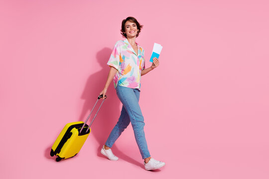 Full length portrait of nice young lady suitcase walk empty space wear shirt isolated on pink color background