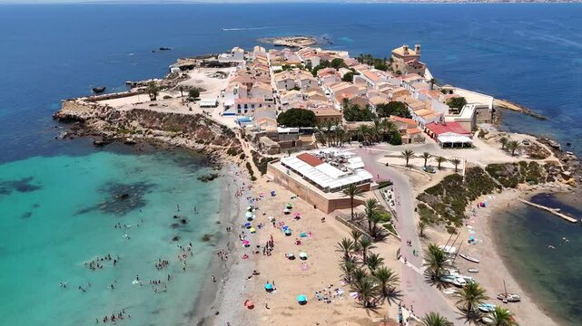 Tabarca Island with San Pedro y San Pablo church, bustling beach and buildings along a vast blue sea