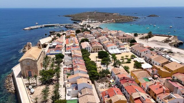 Tabarca Island with San Pedro y San Pablo church, bustling beach and buildings along blue sea