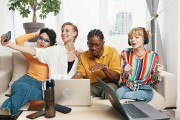 Young adult colleagues working together and socializing in a modern workplace with laptops, taking...