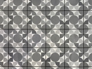 Patterned tiles in modern monochrome geometrical patterns. Circle, square, and diamond shape in repeated pattern, grey, black, and white color. Handmade decorative tiles. Seamless background texture.
