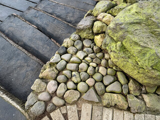 Dark stone path and pebble stone with natural grey rocks with green moss growing, design for landscape outdoor garden. Seamless background texture.