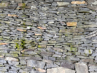 Striped cut combed andesite stone wall cladding stacked on one another. Andesite stone or lavastone for outdoor architectural wall finishing, in grey color. Seamless texture