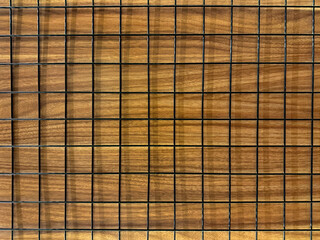 Close up of black wiremesh on top of brown wood panel. Seamless background texture.