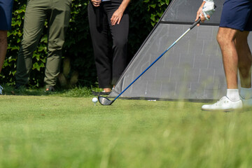  A golfer is captured mid-swing, hitting a golf ball with a driver from a tee. The image highlights...