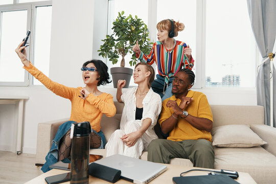 Young adult woman coworkers socializing in modern workplace, diverse colleagues enjoying work break and friendship, Gen Z friends collaborating and relaxing together.