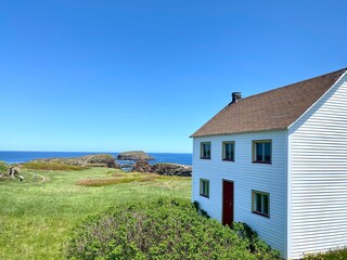 A historic coastal house overlooks the grassy cliffs and ocean at the entrance to the Elliston puffin colony.