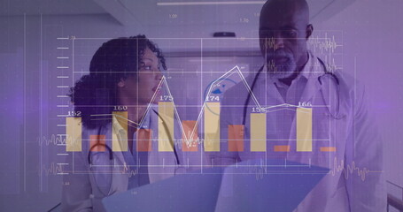 Reviewing charts medical team in lab coats at hospital corridor, with laptop, digital chart overlay