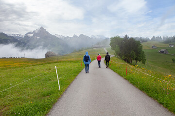 Hiking group on a mountain trail with alpine cabins in the Swiss Alps
