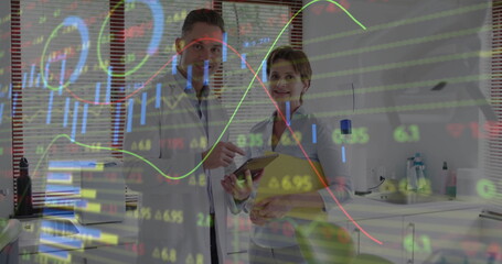 Reviewing stock charts, lab coat professionals holding tablet and clipboard in lab with blinds
