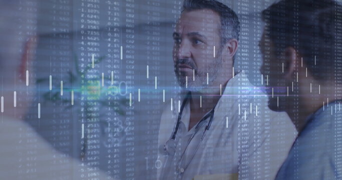 Standing doctor with colleagues analyzing financial data graphics in hospital corridor, with scrubs