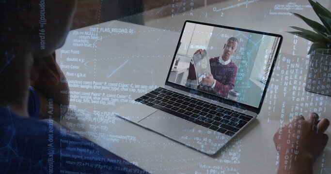 Showing remote engineer holding laptop as coworker typing code at modern office desk, code overlay
